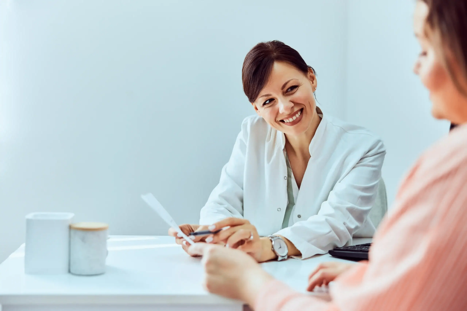 Pharmacist in a white coat reviewing notes with a patient during a personalized weight-loss consultation
