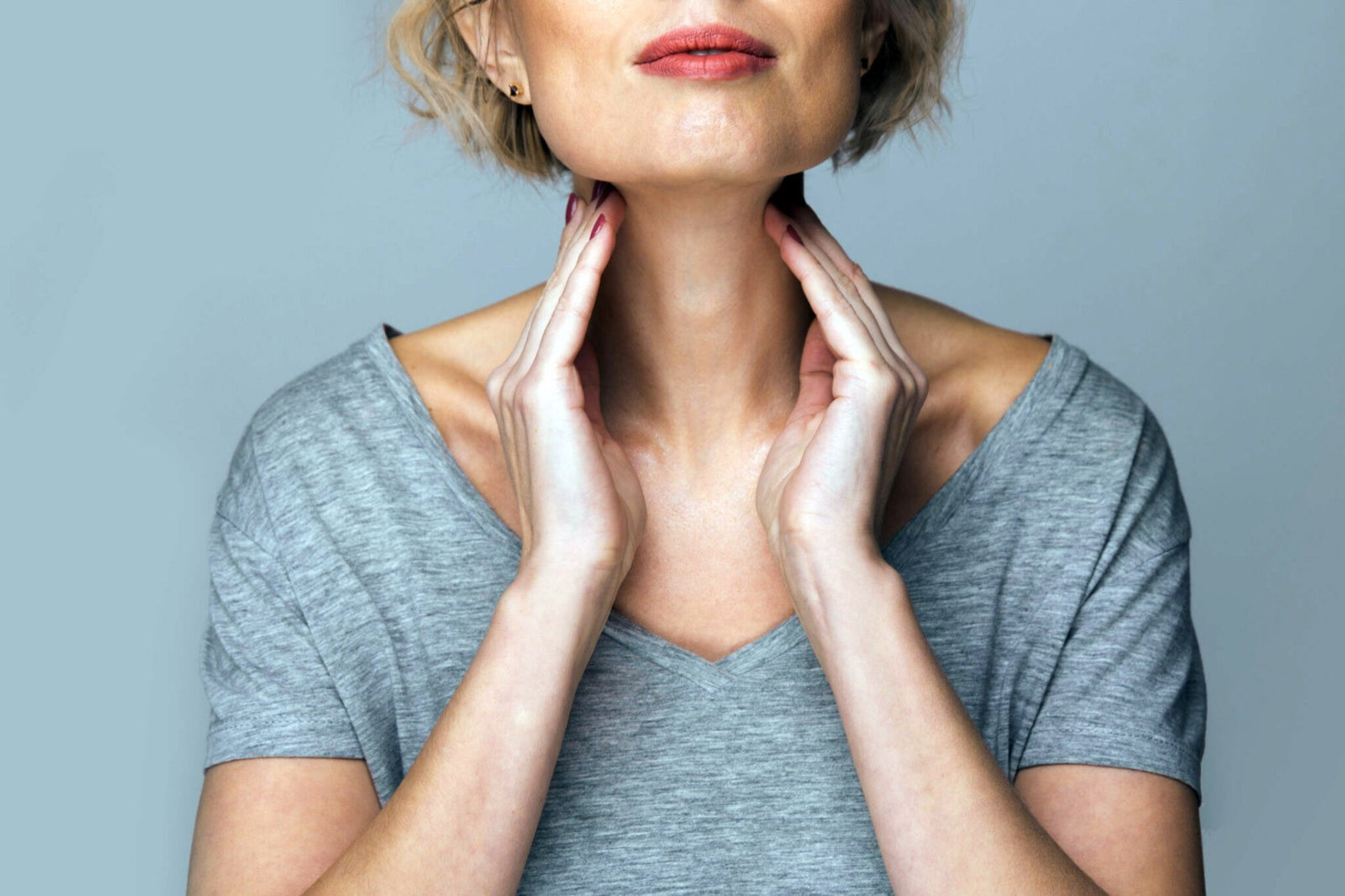 Woman gently touching her neck, representing thyroid health and awareness